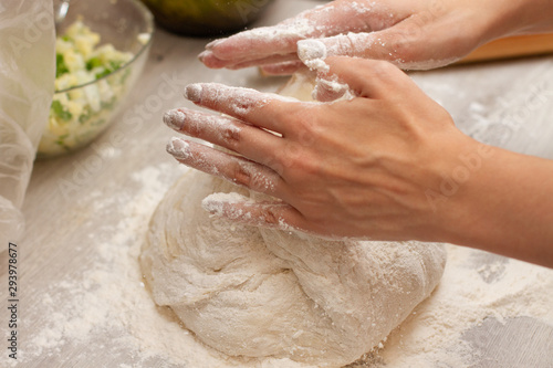 female hands making dough on a table with flour