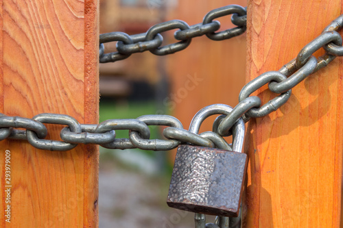 Steel chain with a padlock on the gates of a bright wooden fence