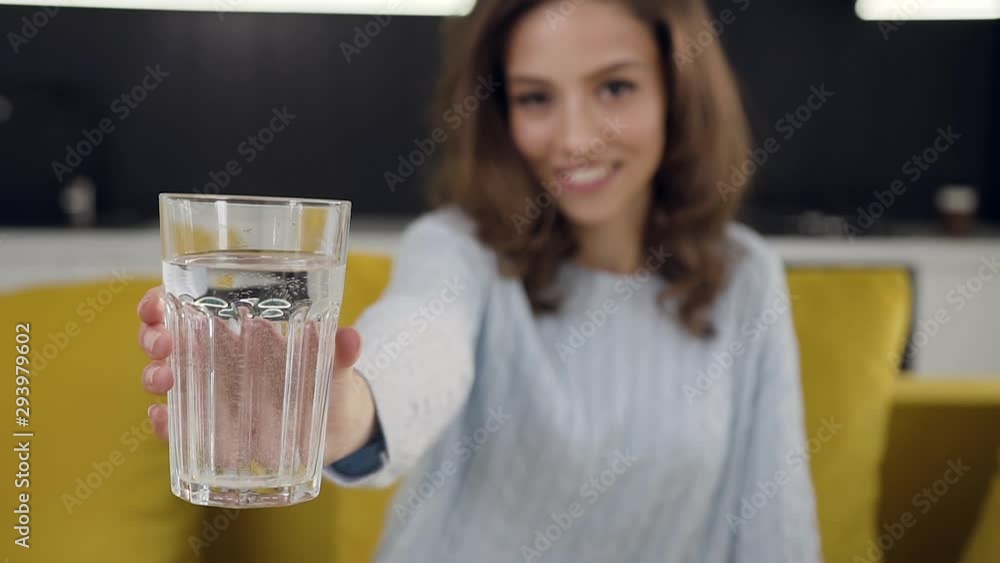 Good-looking smiling 30-aged lady posing on camera with glass of pure water Good-looking smiling 30-aged lady posing on camera with glass of pure water