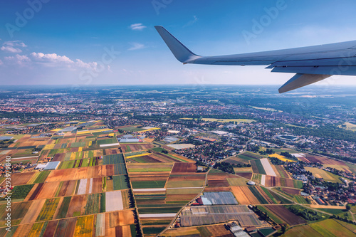 Airplane windows view above the earth on landmark down. View from an airplane window over a wing flying high above farmlands and fields. View from window of plane airplane flying.