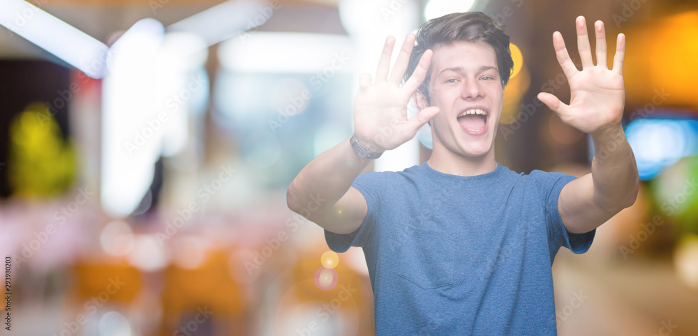 Young handsome man wearing blue t-shirt over isolated background showing and pointing up with fingers number nine while smiling confident and happy. Young handsome man wearing blue t-shirt over isolated background showing and pointing up with fingers number nine while smiling confident and happy.