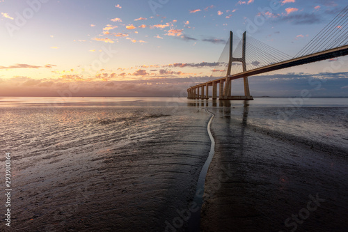 Vasco da Gama bridge at sunrise in Lisbon  Portugal. Vasco da Gama Bridge is a cable-stayed bridge flanked by viaducts and rangeviews that spans the Tagus River in Parque das Na    es in Lisbon.