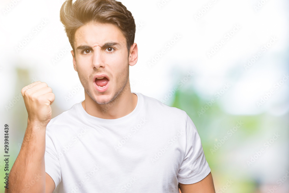 Young handsome man wearing white t-shirt over isolated background angry and mad raising fist frustrated and furious while shouting with anger. Rage and aggressive concept. Young handsome man wearing white t-shirt over isolated background angry and mad raising fist frustrated and furious while shouting with anger. Rage and aggressive concept.