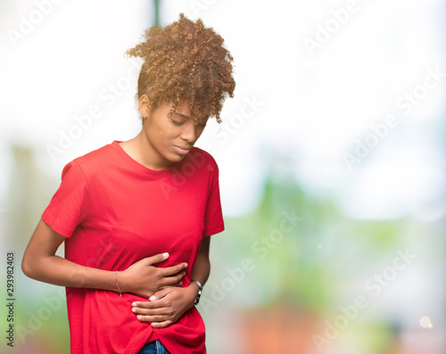 Beautiful young african american woman over isolated background with hand on stomach because indigestion, painful illness feeling unwell. Ache concept. © Krakenimages.com