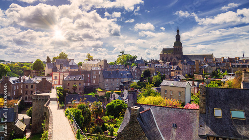 Beautiful view of scenic narrow alley with historic traditional houses and cobbled street in an old town of Dinan with blue sky and clouds. Brittany (Bretagne), France