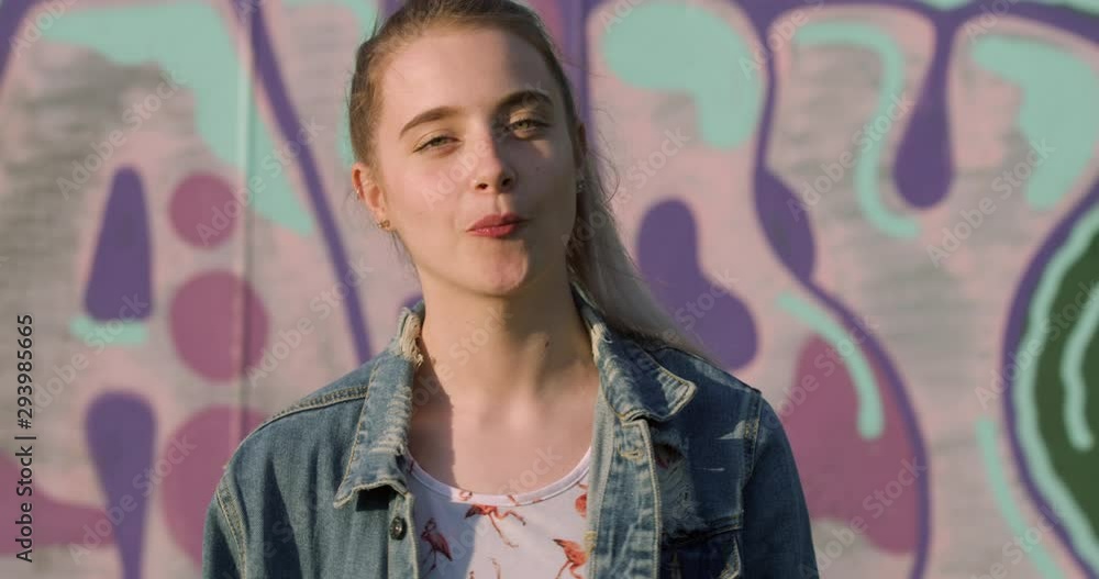 Portrait of Young Blonde Woman blowing Bubble-Gum. Hippy Festival Girl Student in Pink Graffiti Art Setting. Cool Teen Bohemian in Vintage Denim Jacket. A City Fashion Summer Tourist Portrait of Young Blonde Woman blowing Bubble-Gum. Hippy Festival Girl Student in Pink Graffiti Art Setting. Cool Teen Bohemian in Vintage Denim Jacket. A City Fashion Summer Tourist