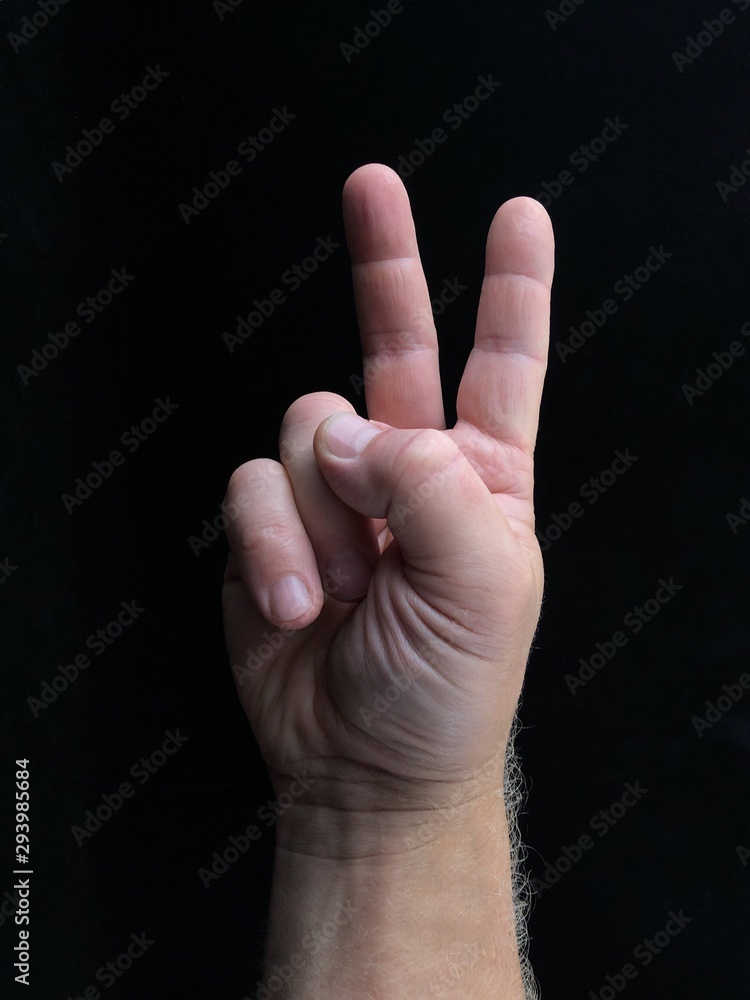 Two fingers up, on a black background. A gesture with two fingers, a sign of freedom. Finger sign, male hand pointing up. Two fingers up, on a black background. A gesture with two fingers, a sign of freedom. Finger sign, male hand pointing up.