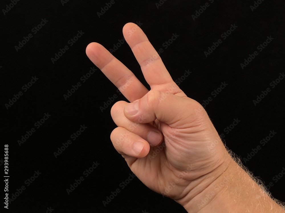 Two fingers up, on a black background. A gesture with two fingers, a sign of freedom. Finger sign, male hand pointing up. Two fingers up, on a black background. A gesture with two fingers, a sign of freedom. Finger sign, male hand pointing up.