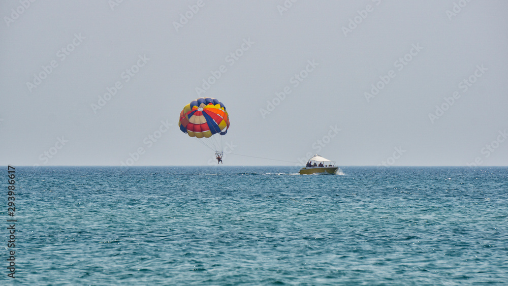 People on a parachute towed behind a boat People on a parachute towed behind a boat