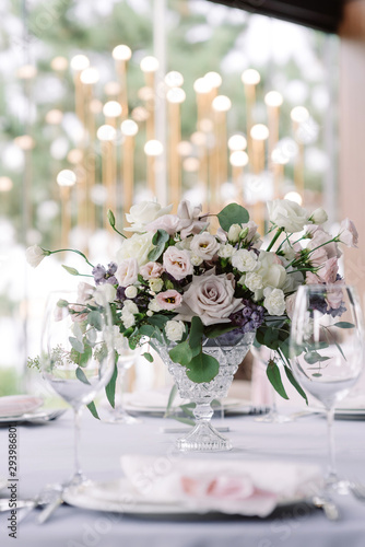 Elegant flowers in a glass vase decorate a wedding table for guests of the groom and bride in the restaurant © Olga