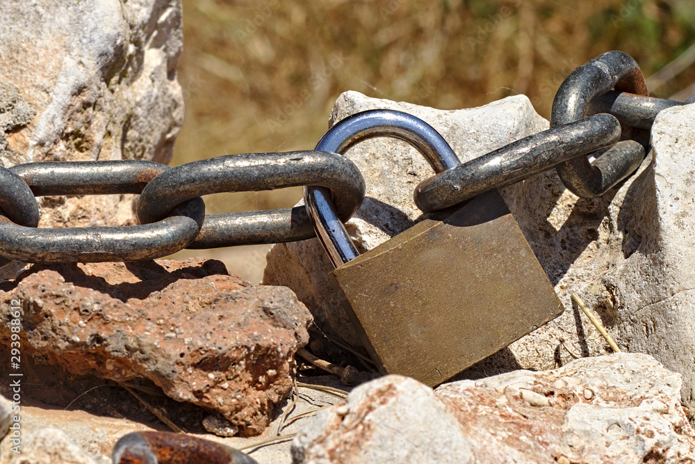 steel chain connected with a padlock going along rocks steel chain connected with a padlock going along rocks