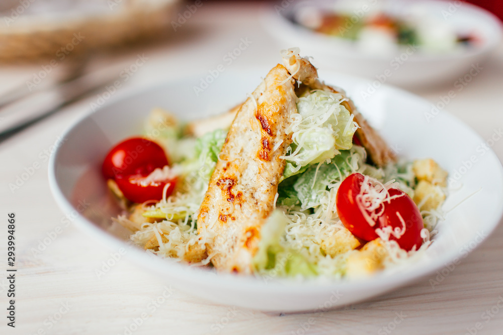 Fresh healthy caesar salad with chicken on white wooden table with fork and knife. Top view. Selective focus. Fresh healthy caesar salad with chicken on white wooden table with fork and knife. Top view. Selective focus.