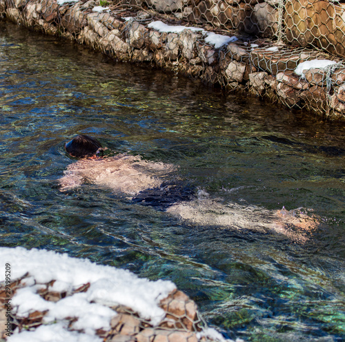 A man bathes in a river in winter