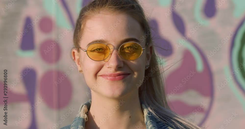 Portrait of Young Blonde Woman in Sunglasses. Festival Girl Student in Hippy Shades and Nose Pierce. Cool Teen by a Pink Bubble Graffiti Art Setting. A Colourful City Fashion Summer Tourist