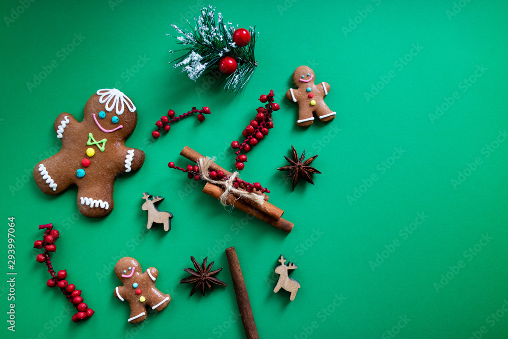 Christmas flat lay with gingerbread men, deers and other ornaments on green background.