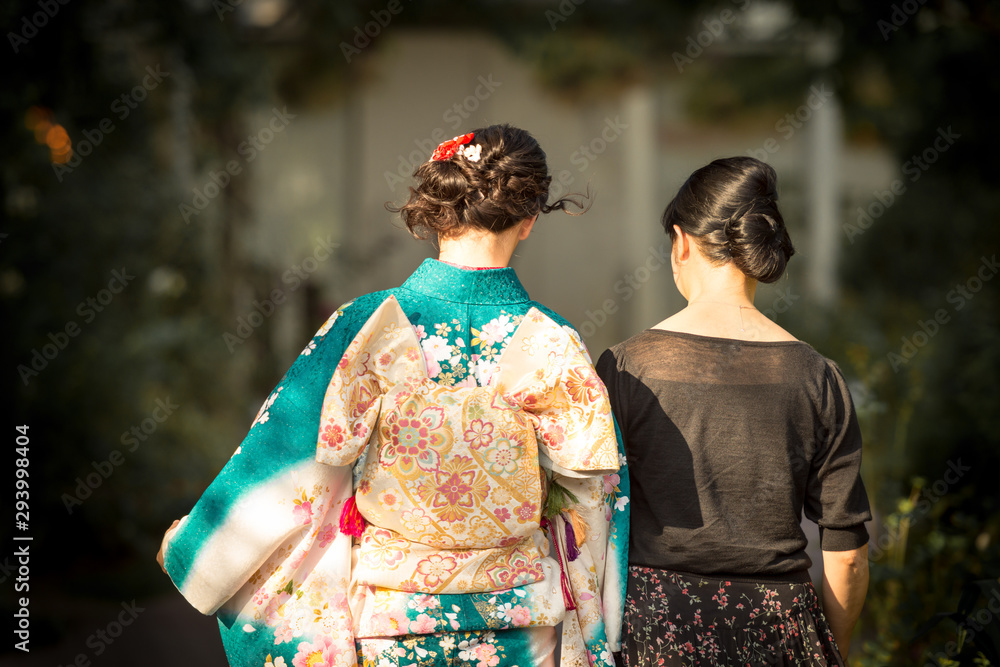 A Japanese woman wearing kimono accompanied by another woman in black dress. A Japanese woman wearing kimono accompanied by another woman in black dress.