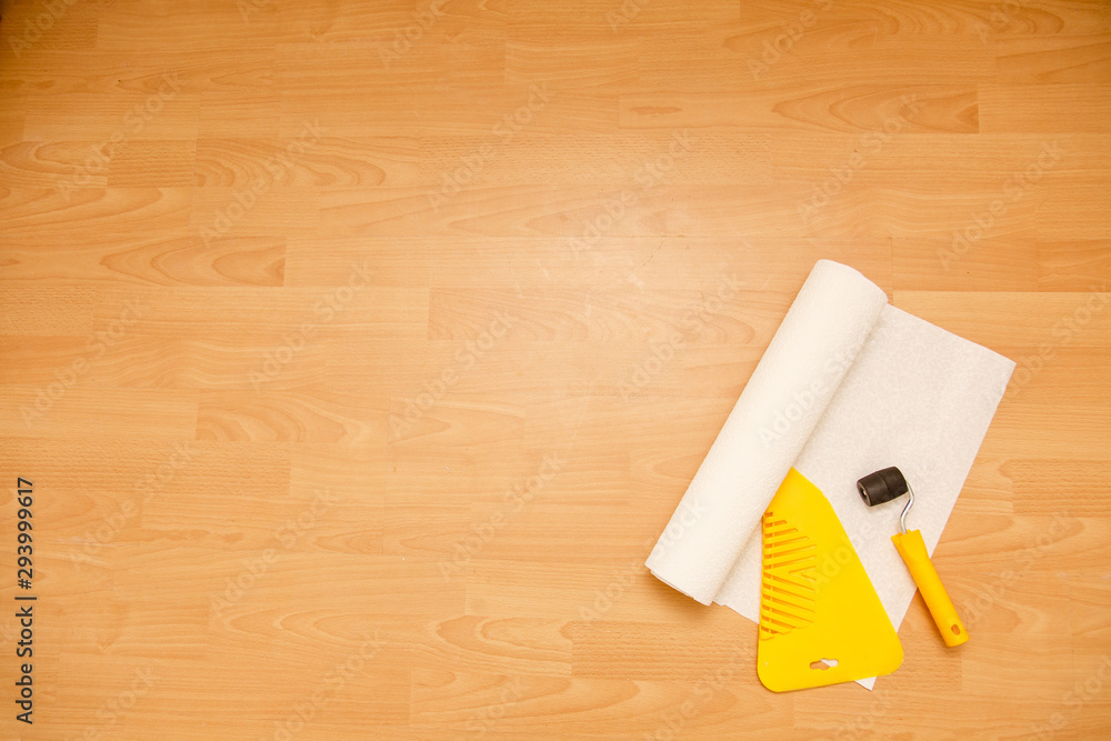 Tools for gluing wallpapers on the laminate floor. A room after renovation. Fresh repair in a room. Tools for gluing wallpapers on the laminate floor. A room after renovation. Fresh repair in a room.