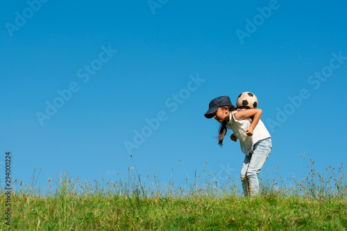 草原でサッカーボールで遊ぶ女の子