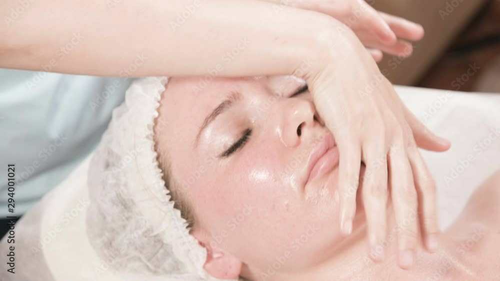 Close-up Spa facial Massage. Girl professional massage therapist does a relaxing facial massage to an attractive client of a spa salon Close-up Spa facial Massage. Girl professional massage therapist does a relaxing facial massage to an attractive client of a spa salon