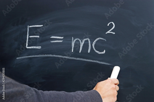 Fototapeta hand of a young person writing the Einstein formula on a blackboard