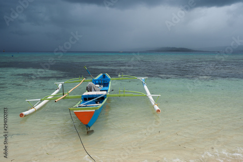Fototapeta Naklejka Na Ścianę i Meble -  Outrigger canoe under tropical rain storm, Gangga Island, Sulawesi Indonesia.