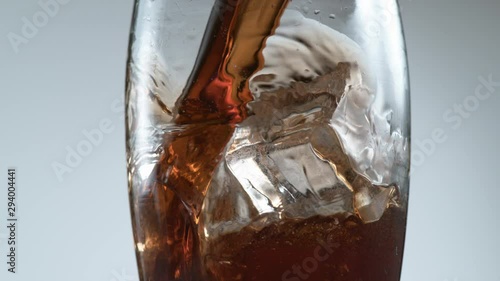 Pouring cola over ice in super slow motion