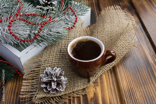 Black  coffee in the  brown ceramic cup and Christmas composition on the rustic wooden  background. Copy space. Closeup.