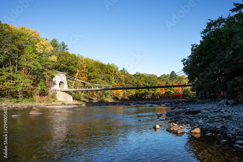 View of the Wire Bridge from the Carrabassett River during peak foliage season in western Maine. Photographed on October 5, 2019. photo