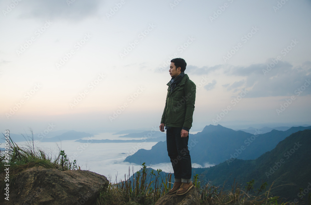 Obraz premium young man standing on hill is wearing green coat