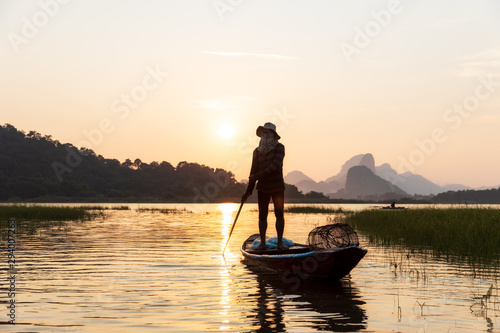 Silhouette of Asian Fishermen paddling wooden boat prepare fishing on the lake In the evening  sunset. Concept Fisherman s Lifestyle in countryside. Lopburi  Thailand  Asia