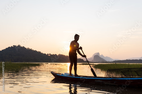 Silhouette of Asian Fishermen paddling wooden boat prepare fishing on the lake In the evening, sunset. Concept Fisherman's Lifestyle in countryside. Lopburi, Thailand, Asia © xreflex