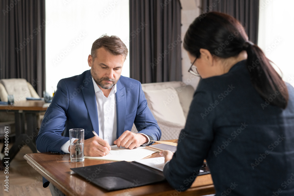 Serious businessman and his colleague working by table in restaurant Serious businessman and his colleague working by table in restaurant