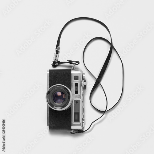 Black film camera and lens with neck strap on isolated background