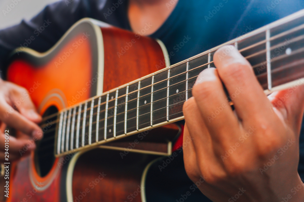 Man's hand playing acoustic guitar, close up