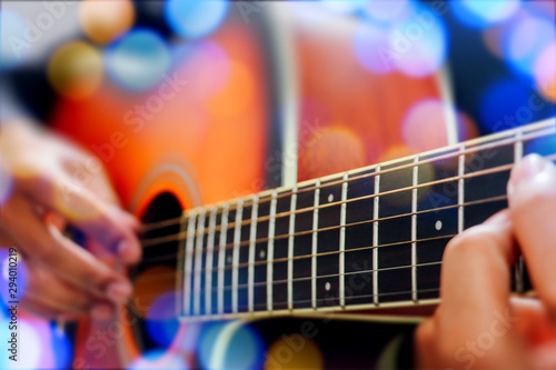 Man's hand playing acoustic guitar, close up. Bokeh