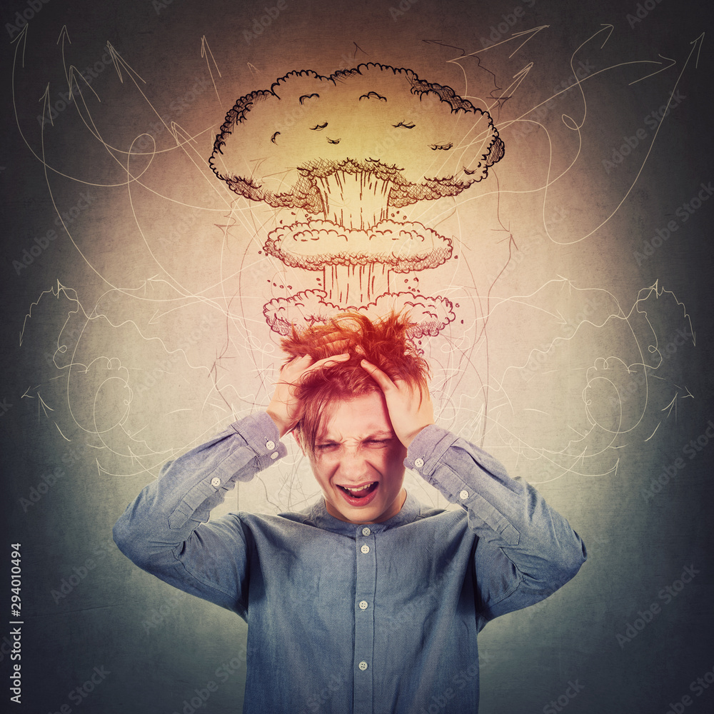 Desperate teenage boy, hands to head, messing up hair and screaming