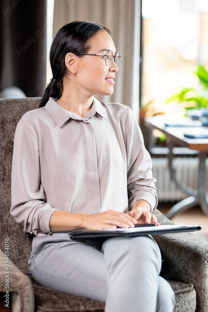 Young elegant female employee sitting in soft comfortable armchair Young elegant female employee sitting in soft comfortable armchair