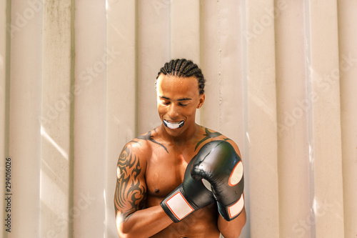 Male boxer with mouth guard outdoors. Tired and sweaty athlete with boxer gloves resting after training. photo