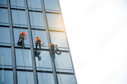 Group of workers cleaning windows service on high rise building - High building and Risk working.