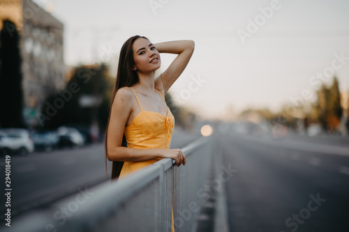 A young woman stands on a background of cityscape.