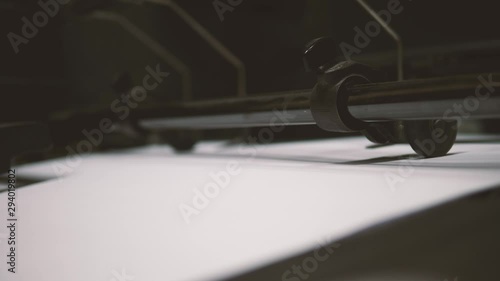 Large sheets of paper rolling through vintage printing machine with sound, close up, loopable 4K video
