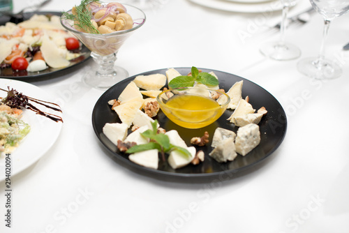 cheese platter with honey and nuts on white restaurant plate dish on the table.