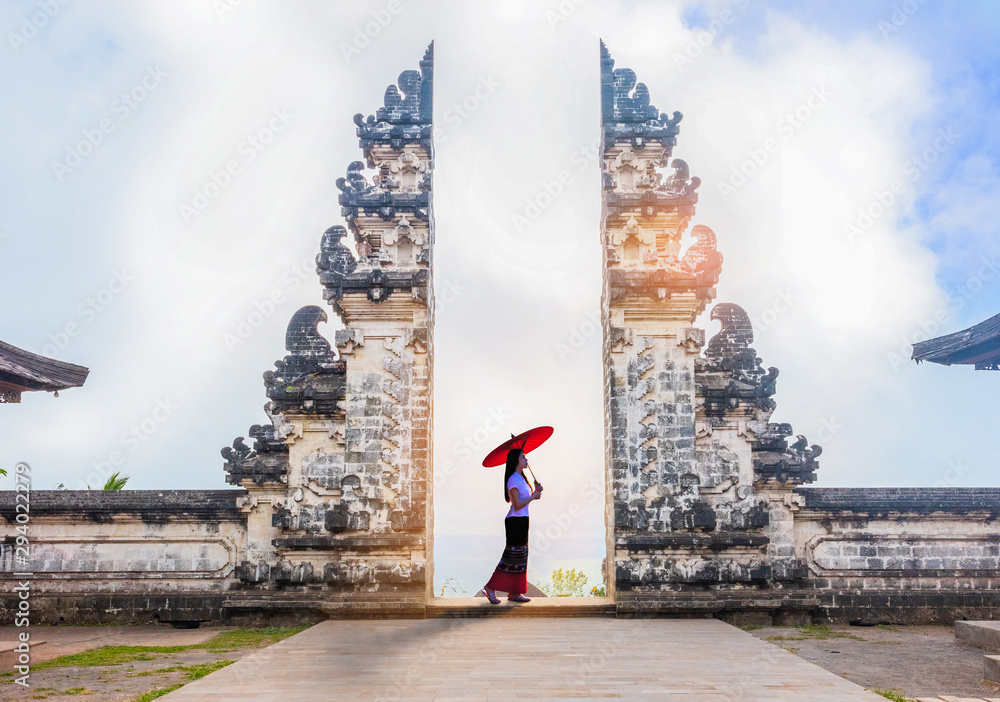 Φωτογραφία Woman holding red umbrella in temple gates at Lempuyang Luhur temple in Bali, In