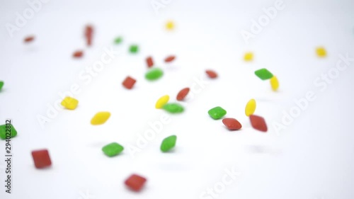 Colorful square candies slowly falling down on a white backdrop