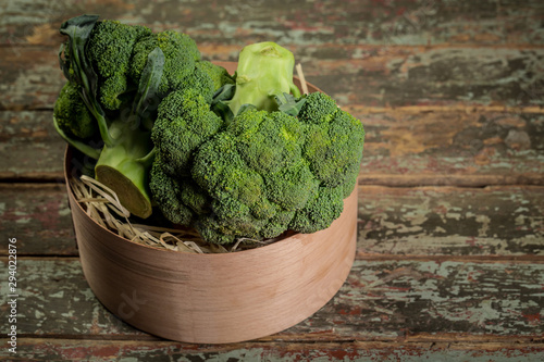 Fresh broccoli in bowl on wooden table close up. Organic food