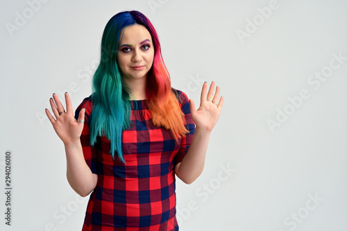 Portrait of a pretty girl with multi-colored hair and make-up on a white background. Stands with a smile in various poses in the studio.