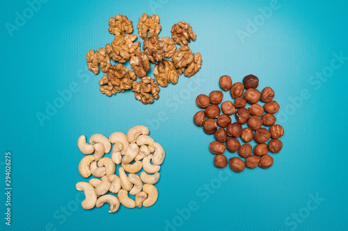 Hazelnuts, walnuts and cashews on a blue background. Set nuts studio image.