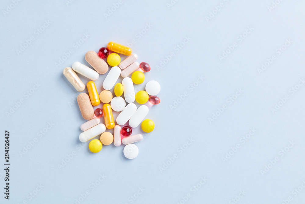 Multicolor vitamins and supplements on bright paper background. Top view. Copy space. Multicolor vitamins and supplements on bright paper background. Top view. Copy space.