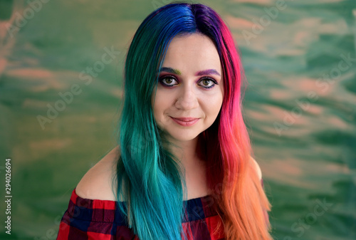 Close-up portrait of a pretty girl with multi-colored hair and make-up on a colored background. Stands with a smile in various poses in the studio. photo