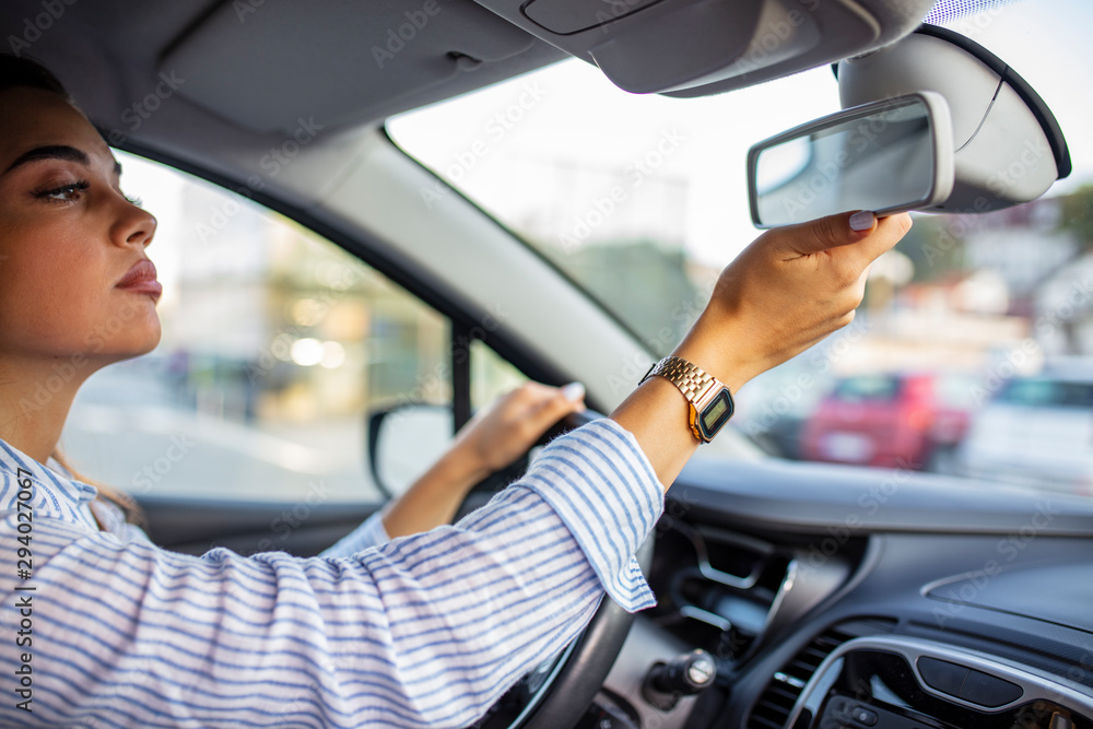 Φωτογραφία Brunette woman sitting on driver's seat and looking in the rear-view mirror